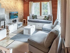 Un salon moderne avec un canapé, un téléviseur et une cheminée.