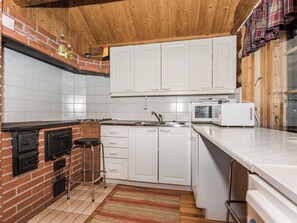 A kitchen with white cabinets, a microwave, and a brick wall. - Vacation home Mikko by Interhome (Hankasalmi)