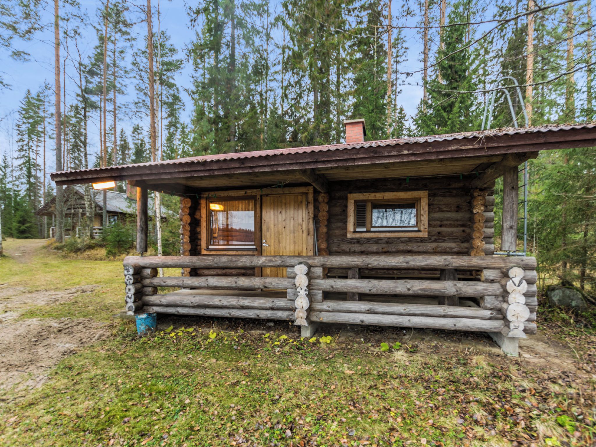 Maalaishenkinen mökki, jossa on puinen kuisti ja yksi ovi.