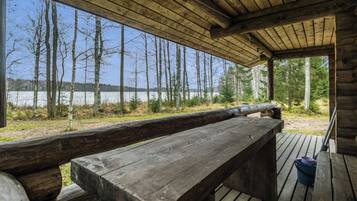 Eine Holzterrasse mit Bänken, mit Blick auf einen See und Wald.
