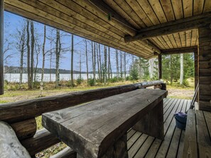 Une terrasse en bois avec des bancs, donnant sur un lac et une forêt.