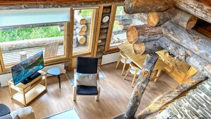 Ein rustikales Holzhaus-Interieur mit Fernseher, Sitzgelegenheiten und Kamin.