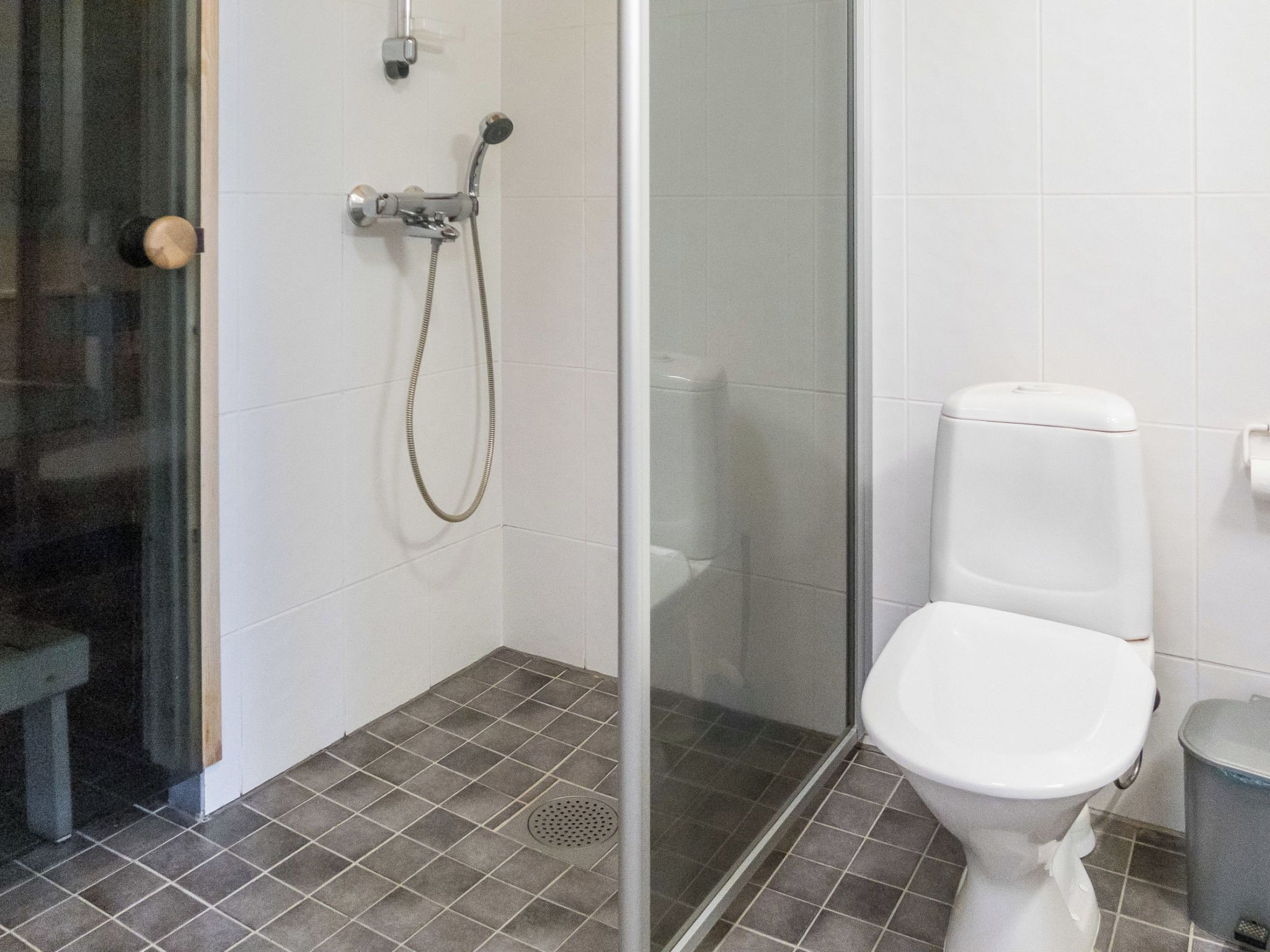 Kylpyhuone, jossa on suihku, wc ja lasiovi.
