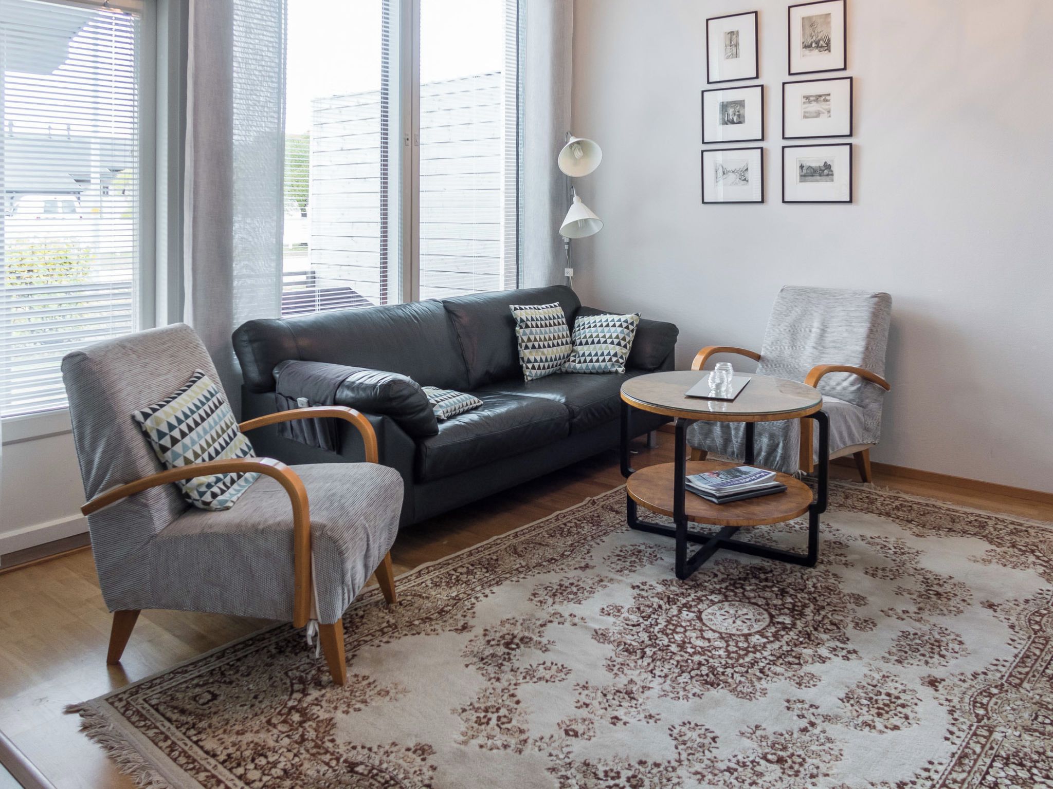 Ein modernes Wohnzimmer mit einem Ledersofa, zwei Sesseln, einem Couchtisch und einem gemusterten Teppich.