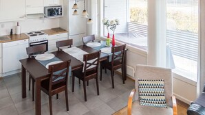 Une cuisine moderne avec des meubles blancs, un four à micro-ondes et un coin repas comprenant une table et des chaises en bois.