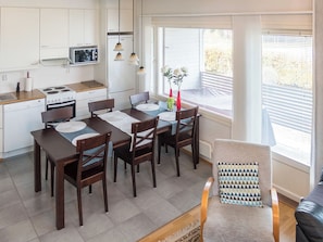 A modern kitchen with white cabinets, a microwave, stove, and a dining area with a table and chairs.