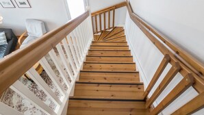 Un escalier en bois avec des rampes blanches et une moquette à motifs.