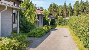 Un chemin qui mène à une rangée de maisons, avec une forêt en arrière-plan.