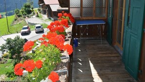 Un balcon en bois offrant une vue sur un paysage montagneux, avec une table et une porte.