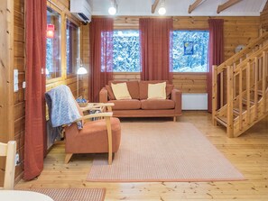 Un interior de cabaña acogedor con sofá, sillón y escalera de madera.