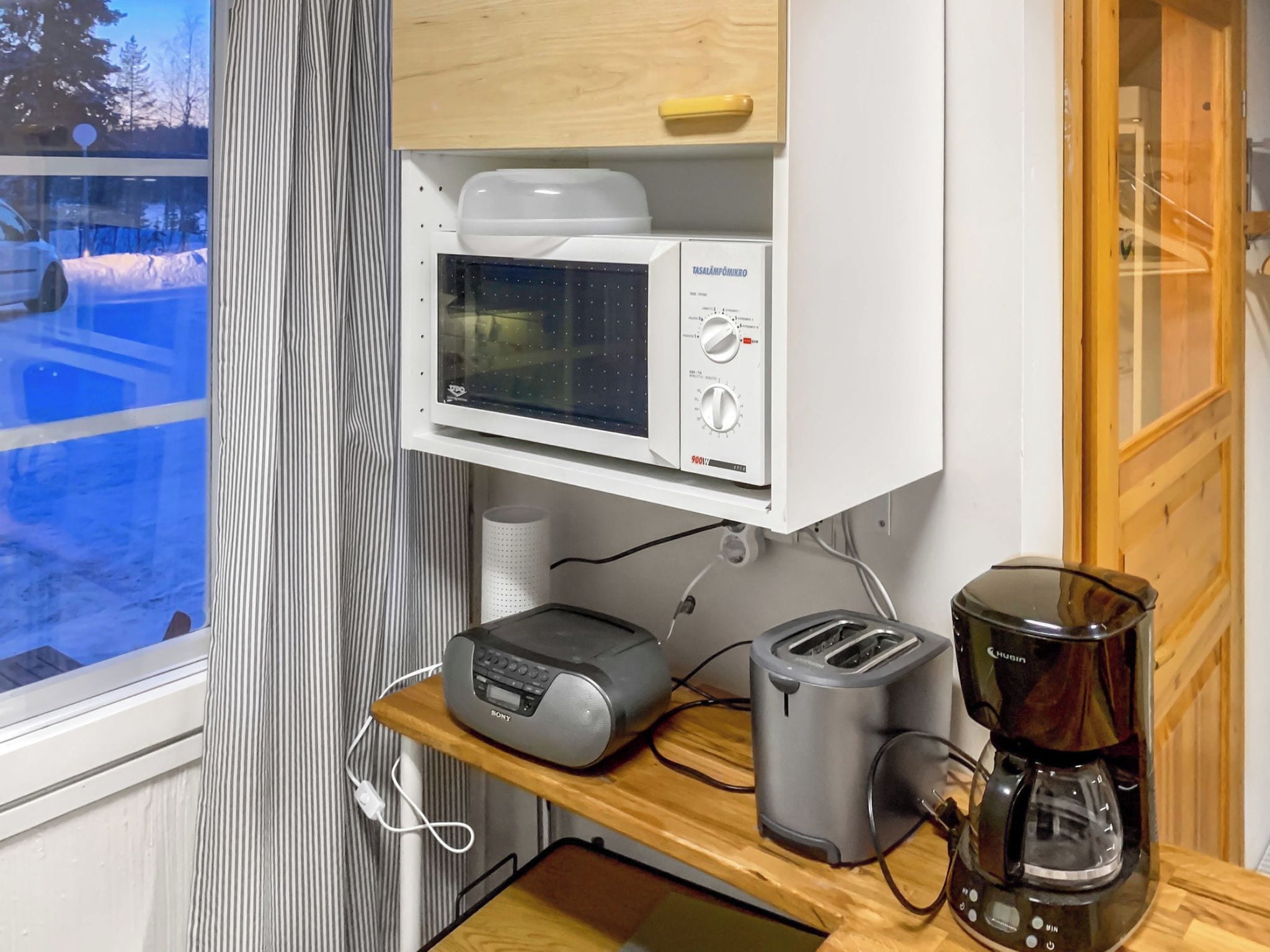 A kitchenette with a microwave, toaster, and coffee maker on a wooden countertop.