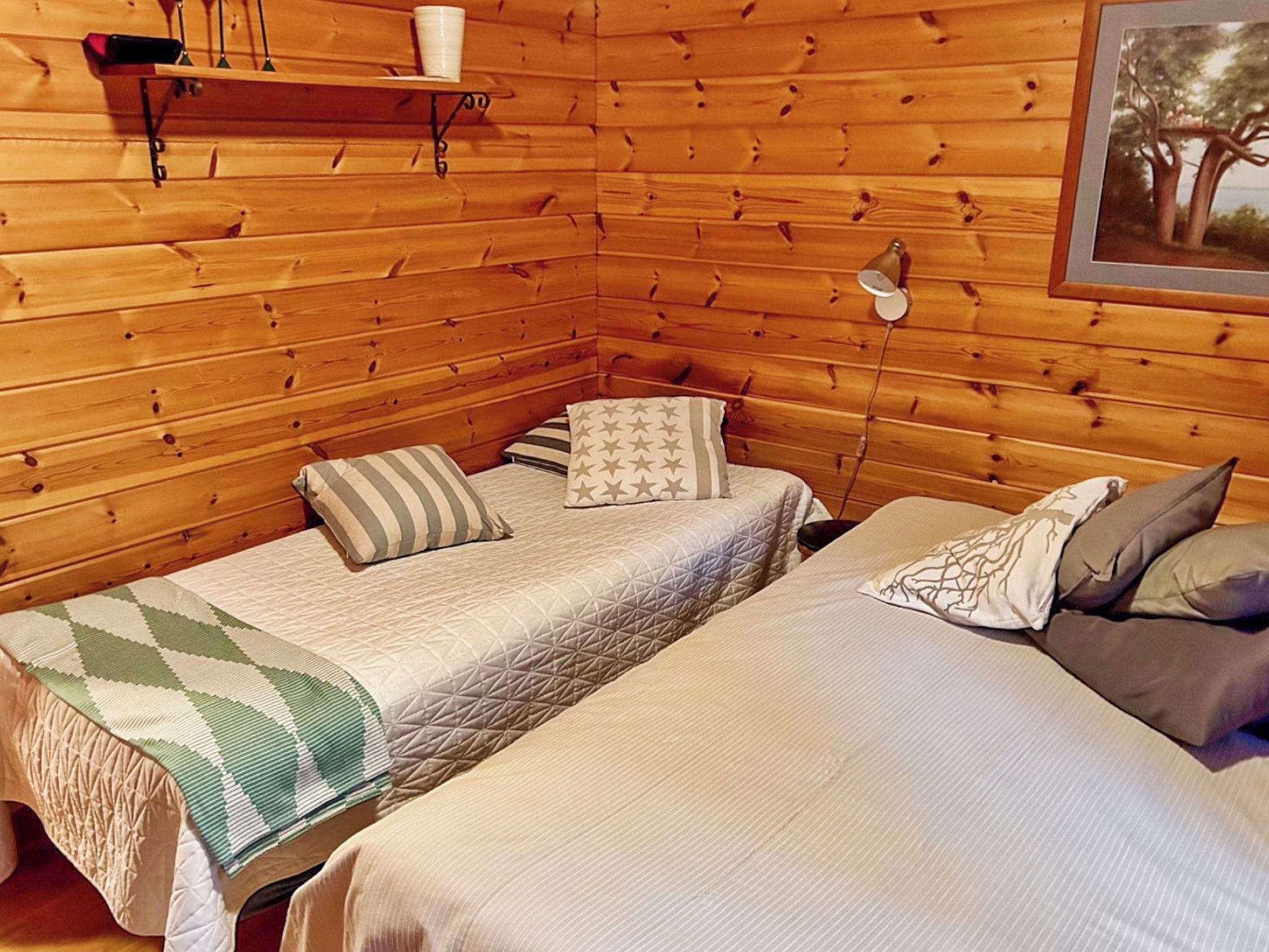 Une chambre de style cabane avec deux lits, une étagère avec une tasse et une lampe.