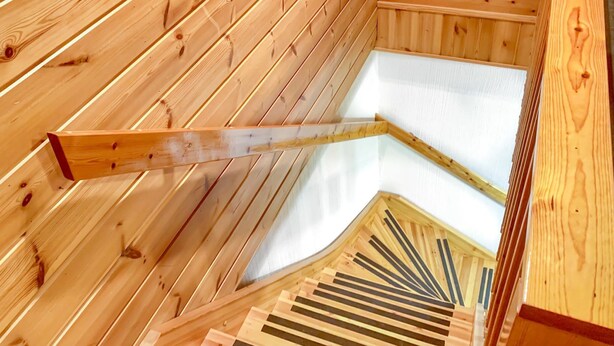 A wooden interior with a sloped ceiling and a wooden staircase.