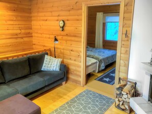 Una habitación tipo cabaña con sofá, cama, reloj y chimenea.