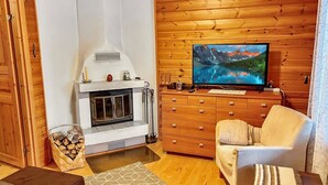 A cozy cabin interior with a fireplace, a television, wooden walls, and a comfortable seating area.