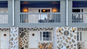 A two-story building with a balcony, stone wall accents, and a door with a round window.