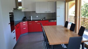 Una cucina moderna con mobili rossi, un tavolo da pranzo in legno e un'ampia finestra.
