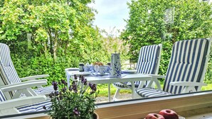A dining area with a table set for two, surrounded by striped chairs, a potted plant, and a bowl of apples on a windowsill. - Vergissmeinnicht by Interhome (Dittishausen)