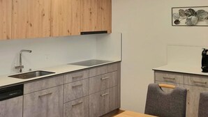 Une cuisine moderne avec des meubles en bois, un évier en acier inoxydable et un coin repas comprenant une table et des chaises.