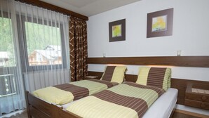 Une chambre à coucher avec un lit en bois, des rideaux blancs et deux tableaux encadrés accrochés au mur.