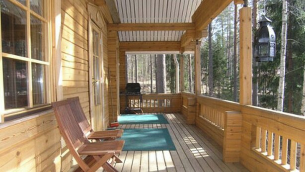 A wooden deck with a covered area, wooden chairs, and a grill. - Mustikka by Interhome (Lohja)