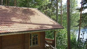 A wooden cabin with a tiled roof, a wooden staircase, and a view of a forested area. - Mustikka by Interhome (Lohja)
