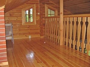 Experience the rustic charm of this spacious room with a high ceiling, wooden walls, and polished floor.