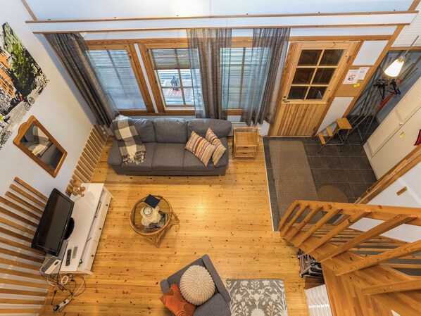 A modern living room with a sofa, a television, and a wooden floor.