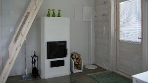 A room with a white fireplace, a wooden ladder, a green rug, and a door with blinds. - Mariantupa by Interhome (Muurame)
