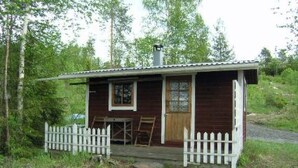A small wooden cabin with a porch and a picket fence, surrounded by greenery. - Mariantupa by Interhome (Muurame)