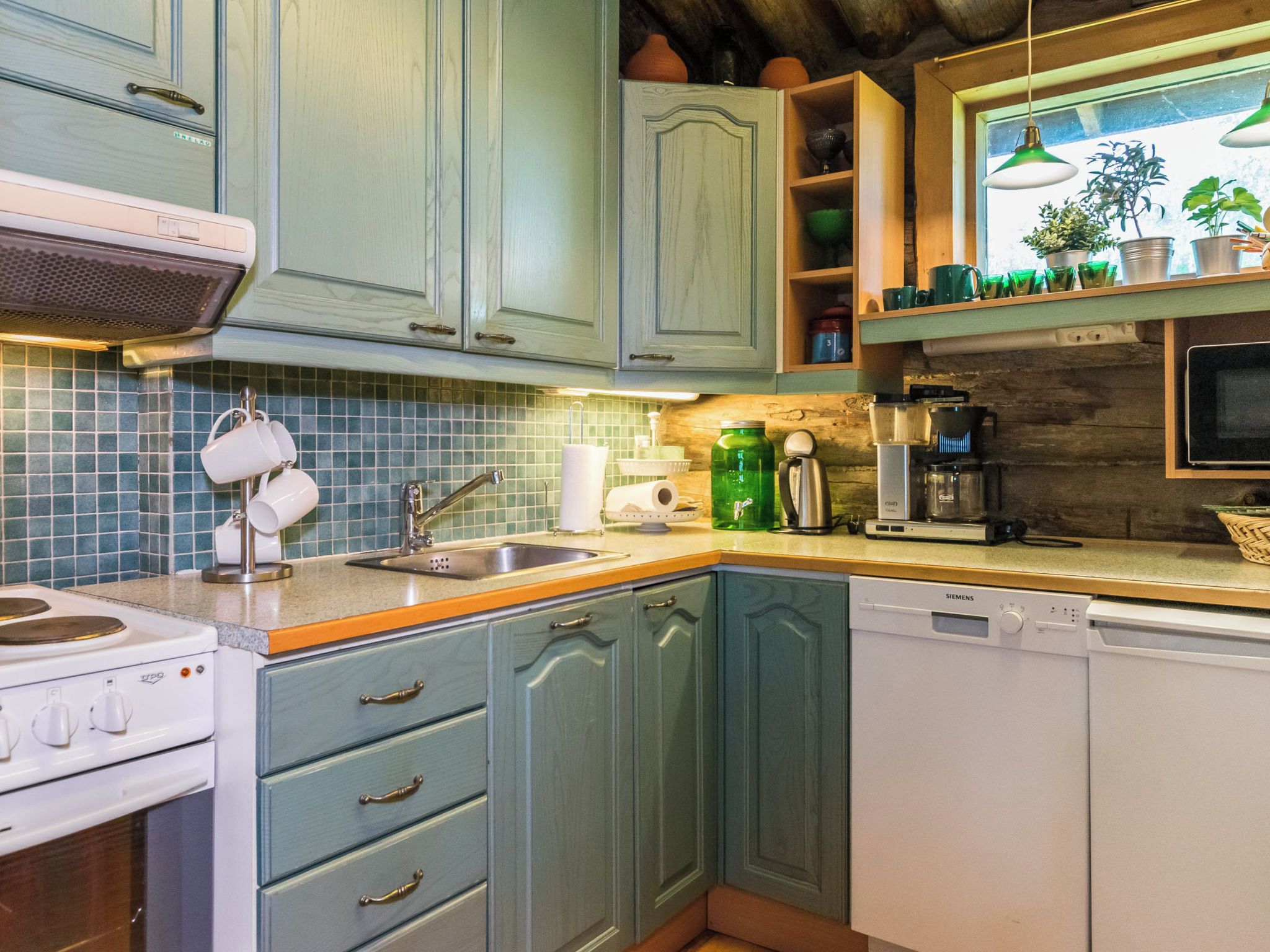 Una cucina con mobili color petrolio, un piano cottura bianco e una lavastoviglie Siemens.