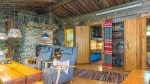 Ein rustikales Blockhaus-Interieur mit Kamin aus Naturstein, Holzmöbeln und einer gemütlichen Sitzecke.