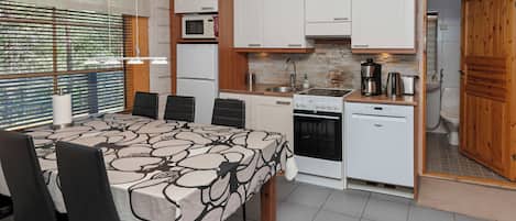 A compact kitchen with a dining area, featuring a stove, microwave, and sink.
