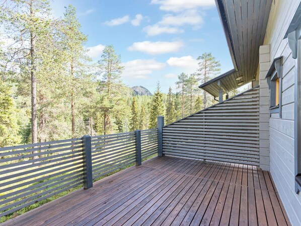 A wooden deck with a railing overlooking a forested area.