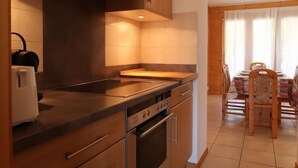 Eine moderne Küche mit Holzschränken, einer schwarzen Arbeitsplatte und einem Essbereich mit Holztisch und Stühlen.