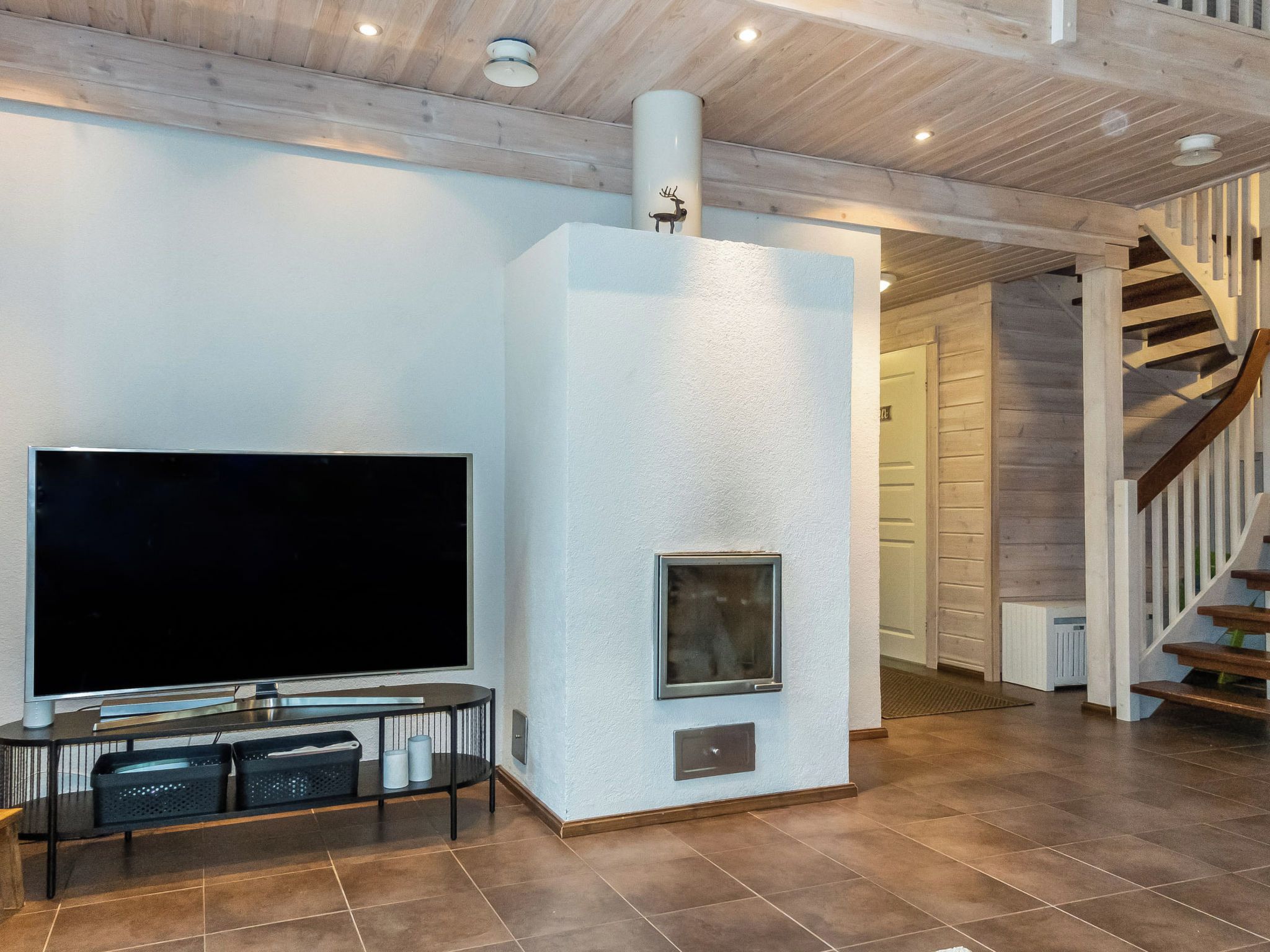 A modern living room with a flat-screen TV, a fireplace, and a staircase.