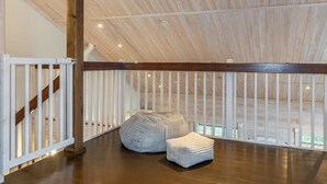 A spacious loft with a high ceiling, wooden beams, and a view of the outdoors.