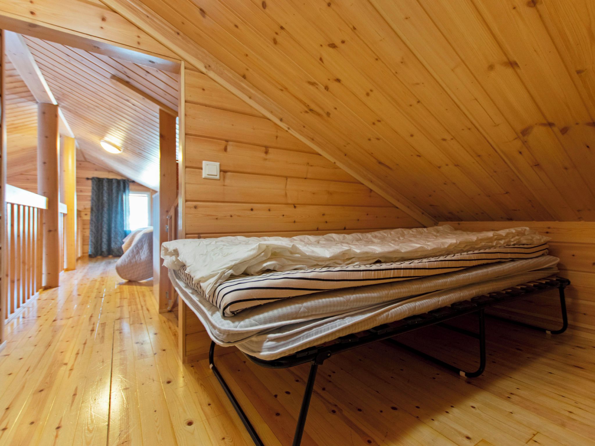 A wooden interior with a bed and a hallway.
