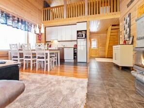 Ein gemütliches Blockhaus-Interieur mit Essbereich, Küche und Kamin.