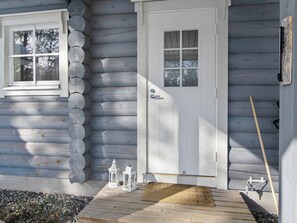 A wooden house with a white door, a window, and a small porch area with a doormat and two lanterns. - Sini-ruka 1 by Interhome (Kuusamo)
