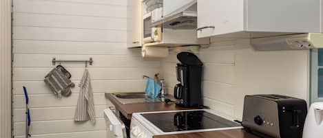 Une cuisine de taille réduite équipée d’une cuisinière, d’un grille-pain et d’une machine à café.