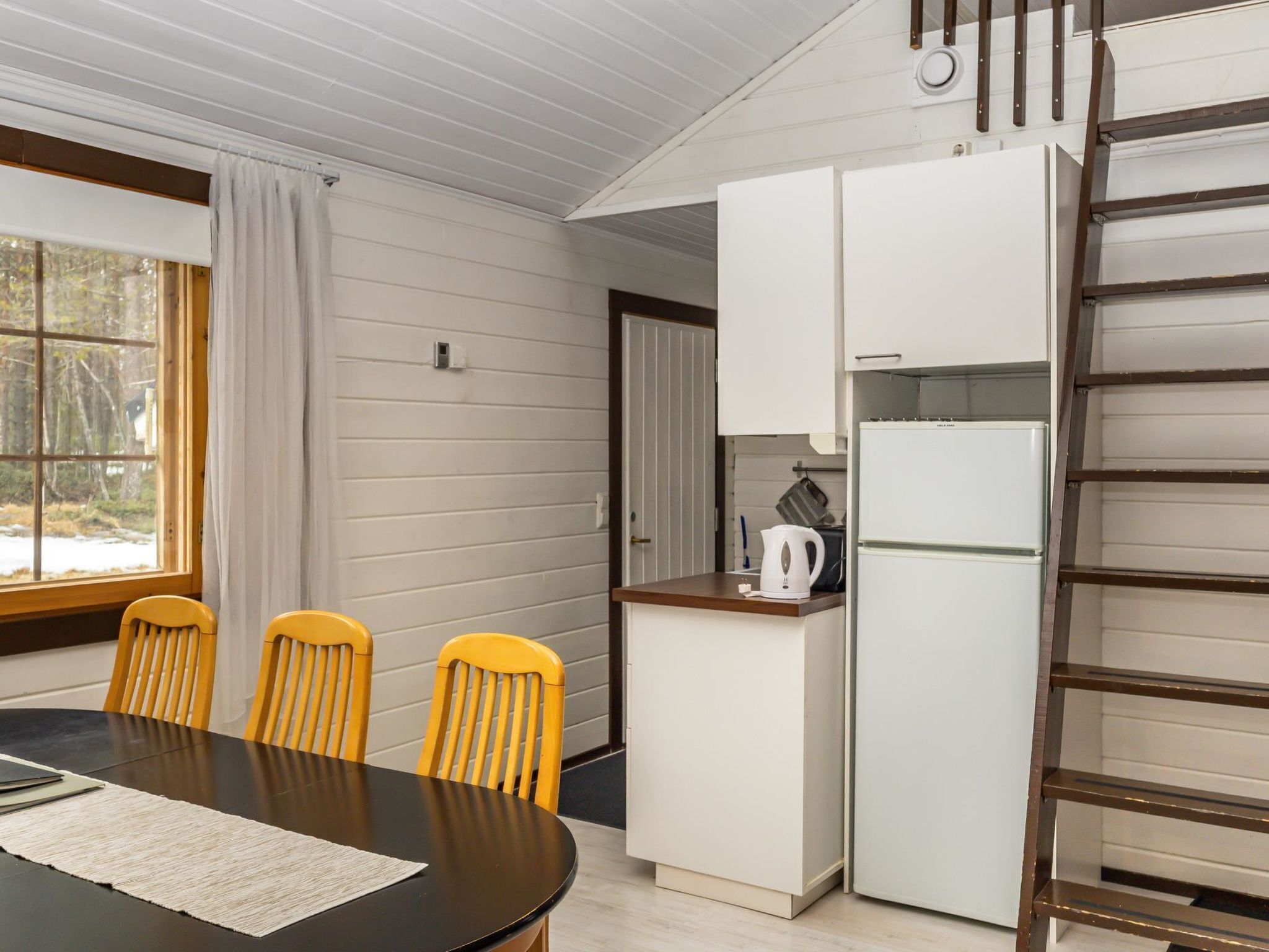 Una cocina compacta con una mesa de comedor, sillas y un refrigerador.
