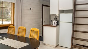 A compact kitchen with a dining table, chairs, and a refrigerator.