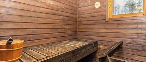 Un sauna avec des murs en bois, un banc et un seau en bois.