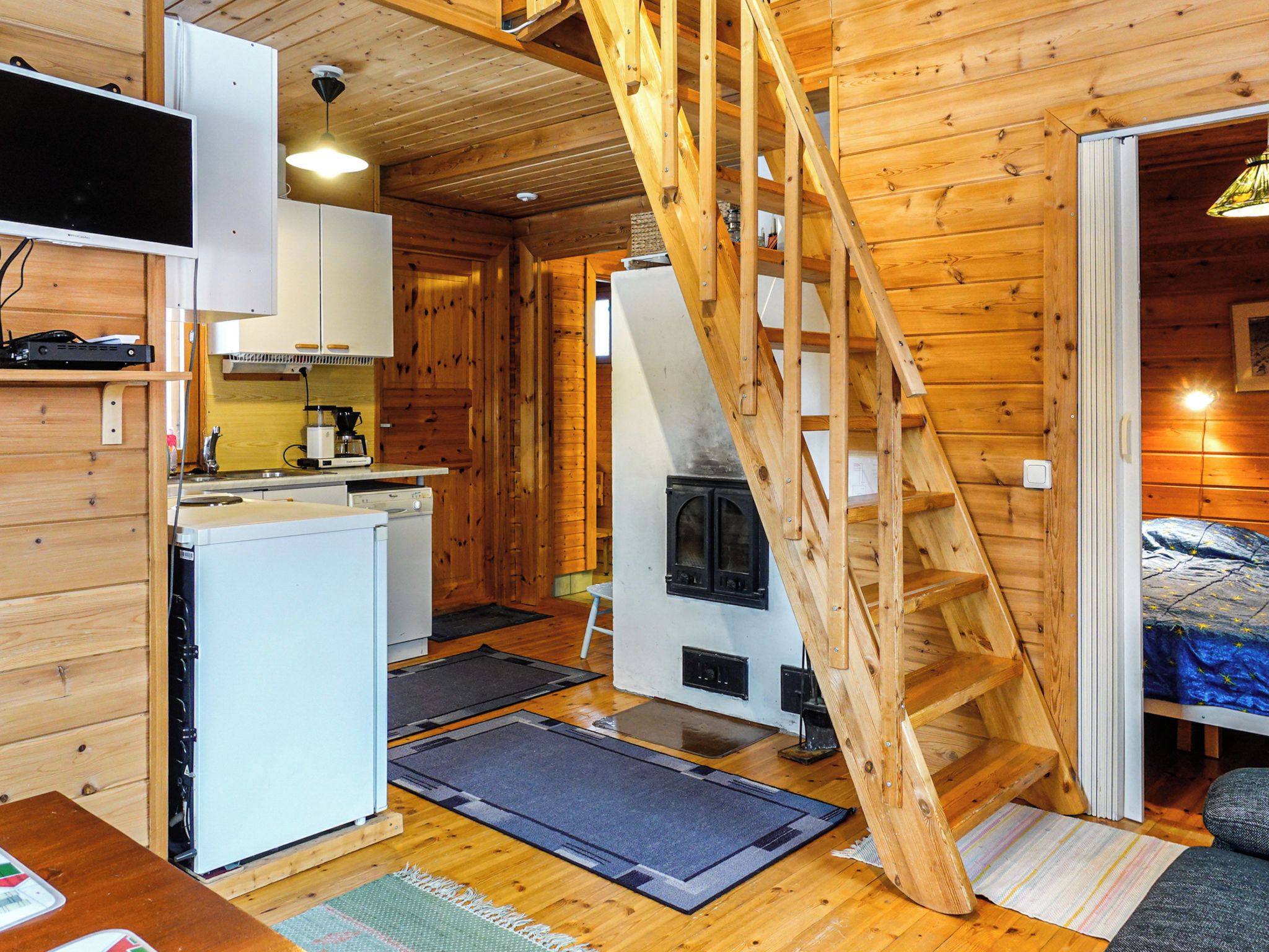 Una cabaña compacta con cocina, comedor, zona de descanso y escalera de madera.