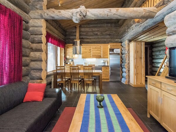 A log cabin interior with a living area, dining space, and kitchen.