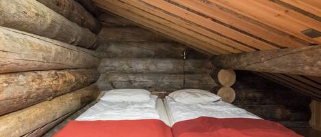 A log cabin room with a bed, a red blanket, and a ceiling light.