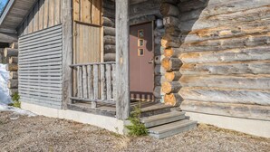 Eine Holzhütte mit einer Holzterrasse, einer braunen Tür und einer kleinen Treppe zum Eingang.
