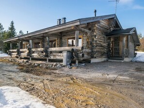 A log cabin with a porch, a chimney, and a metal roof.