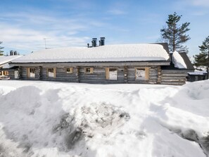 A log cabin with a snow-covered roof, surrounded by snow.